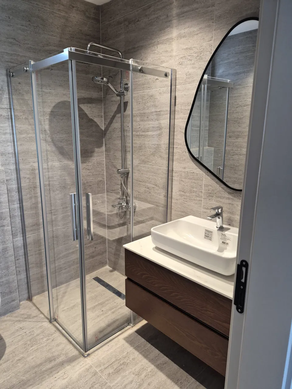 Duşakabin, lavabo dolabı ve aynası tamamlanmış gri seramikli banyo